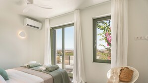 A bedroom with a bed, a chair, a window with curtains, and an air conditioning unit. - Ampelas 4BR Villa, Private Pool, To Ktima Paros (Paros)