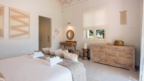 Una camera da letto con un letto grande, una cassettiera in legno, una toeletta con specchio e una finestra vista verde.