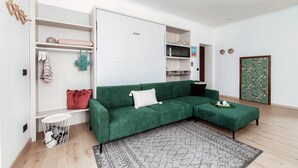 A modern living room with a green sofa, a small round table, and a patterned rug. - Dinghy Studio (Como)