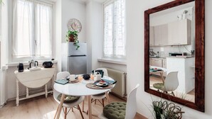A modern kitchen with a dining area, white cabinetry, and a large mirror. - Dinghy Studio (Como)