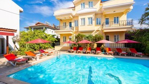 Un hotel con piscina, sombrillas rojas y sillas de descanso.