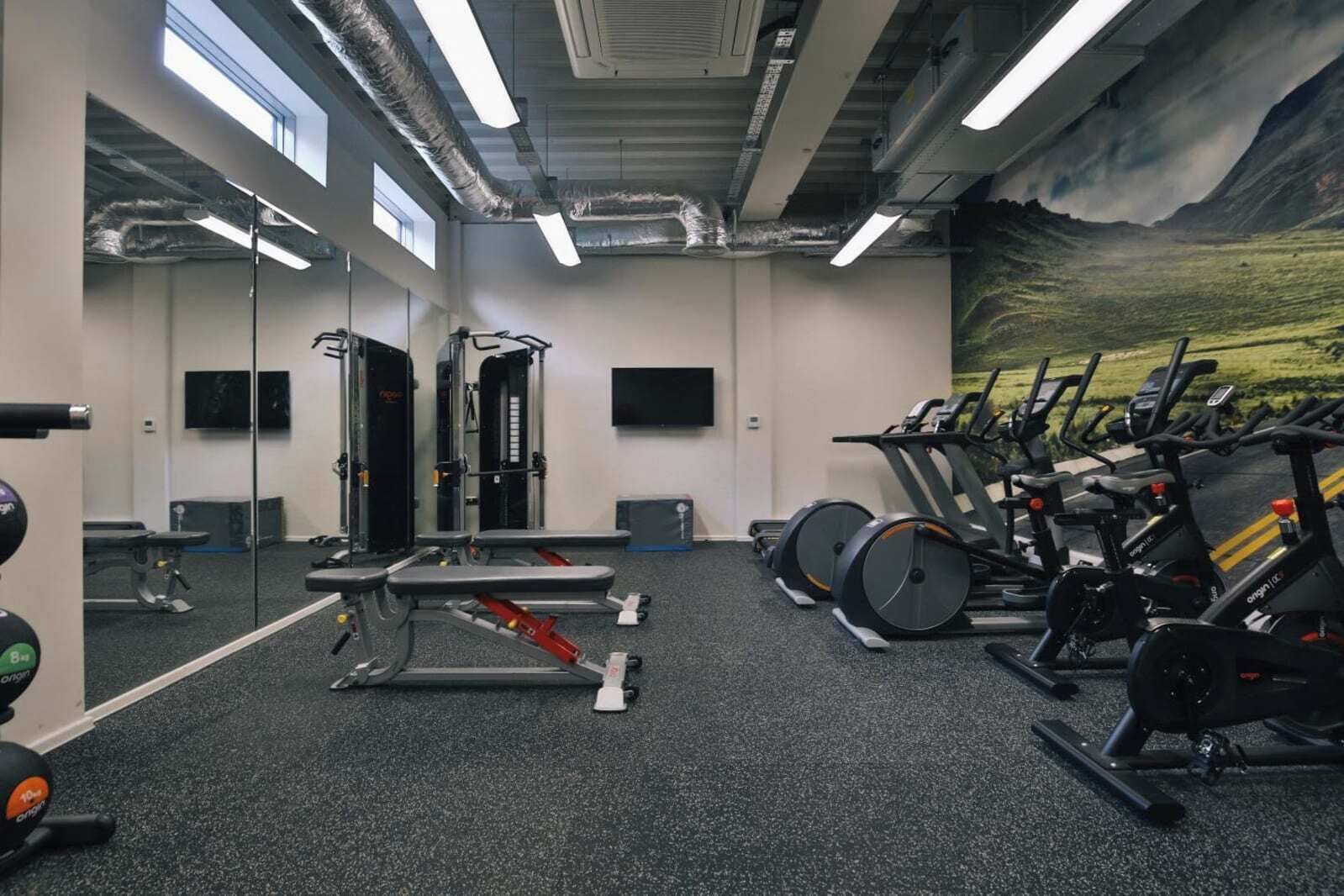 A gym with exercise equipment, a mirror, and a large window.