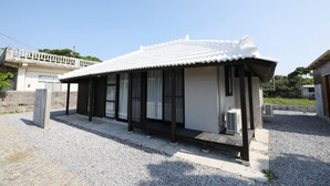 A small, single-story building with a white tiled roof and black-framed windows. - Ryukyu Kominka Yamakawa House (Motobu)