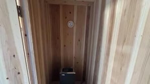 A wooden sauna with a bench, a heater, and a wooden bucket. - Ryukyu Kominka Yamakawa House (Motobu)