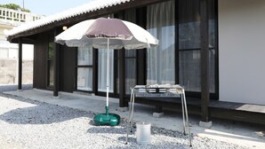 A building with a covered outdoor seating area, a water fountain, and a metal table. - Ryukyu Kominka Yamakawa House (Motobu)