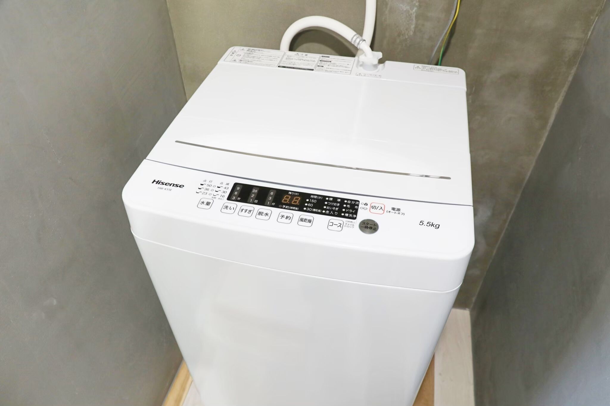A white Hisense washing machine with a control panel, a power cord, and a weight capacity of 5.5kg.