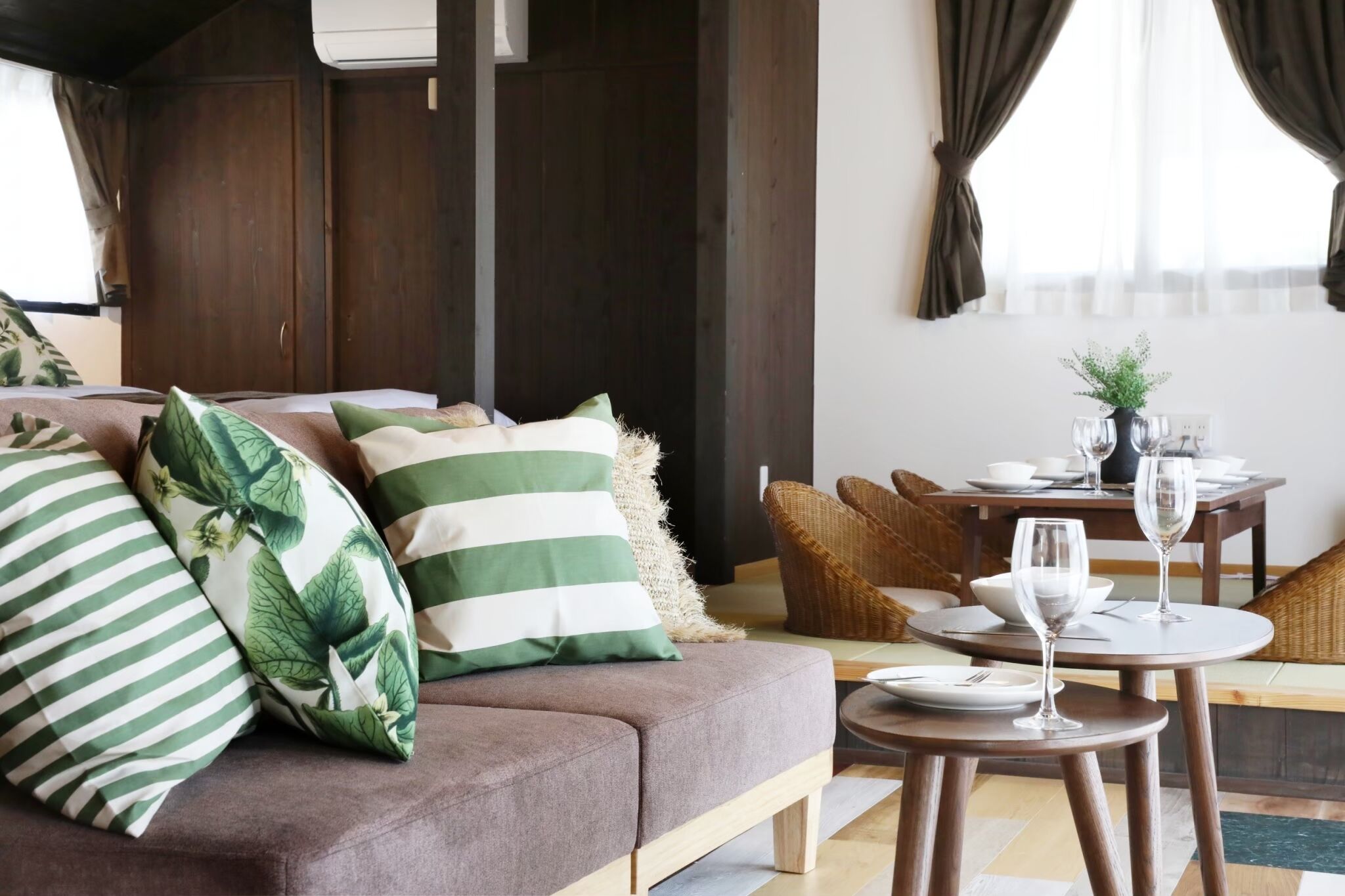 A modern living room with a sofa, striped pillows, a dining table with chairs, and a small plant on the table.