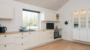 A modern kitchen with white cabinetry, a wooden countertop, a built-in oven, and a window. - 5 Star Holiday Home in Ansager (Ansager)