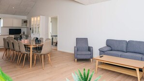 A modern living space with a dining area, a grey armchair, a grey sofa, and a wooden coffee table. - 5 Star Holiday Home in Ansager (Ansager)