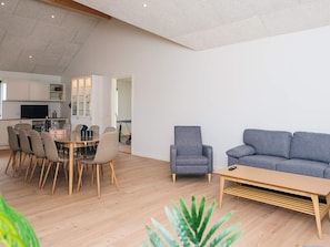 A modern living space with a dining area, a grey armchair, a grey sofa, and a wooden coffee table.