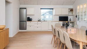 A modern kitchen with a large island, built-in appliances, and a dining area with a round table and chairs. - 5 Star Holiday Home in Ansager (Ansager)