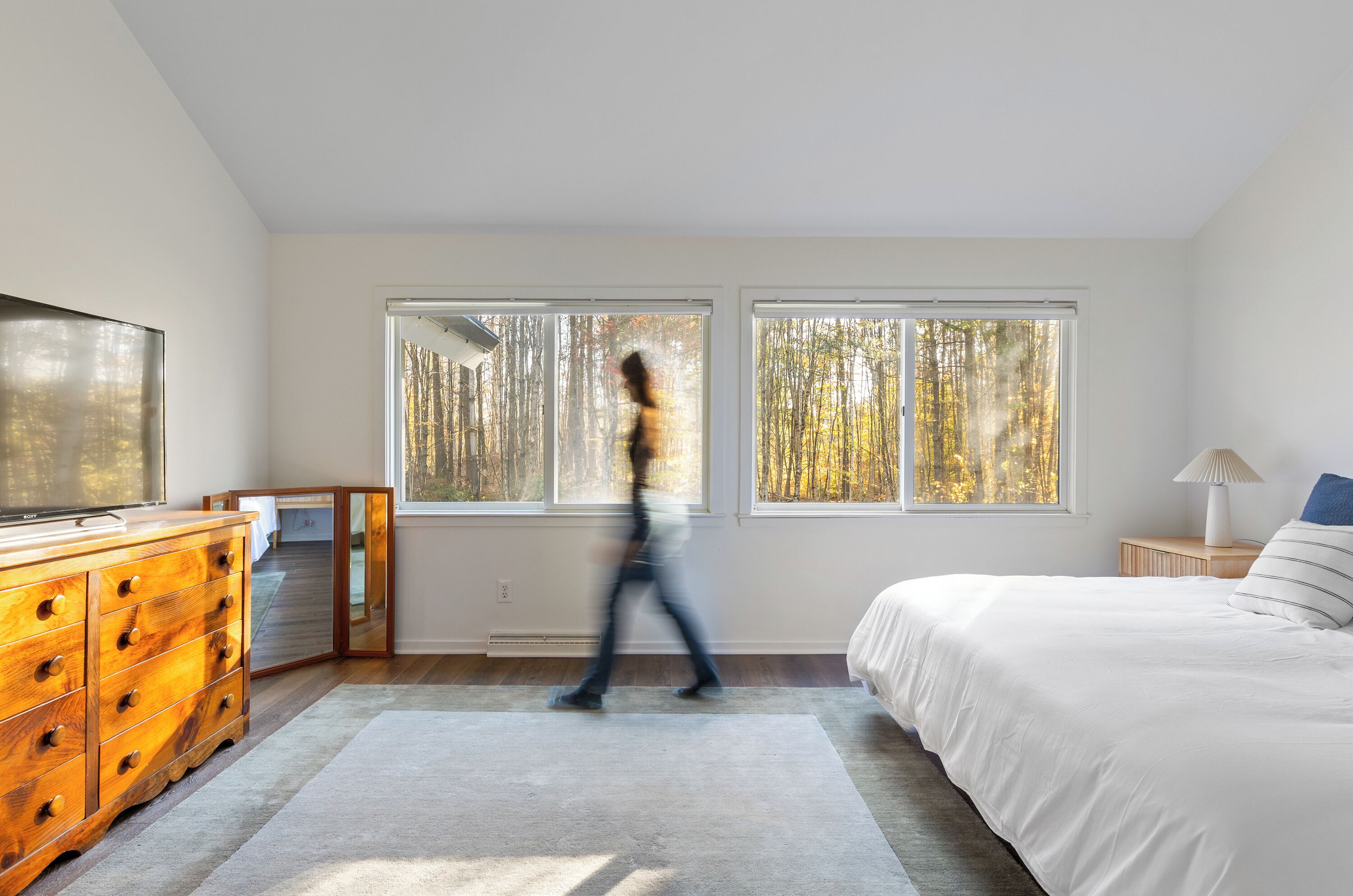 Une chambre à coucher avec un lit, une commode et de grandes fenêtres.