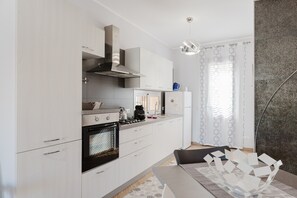 A modern kitchen with white cabinets, a stove, and a coffee maker.