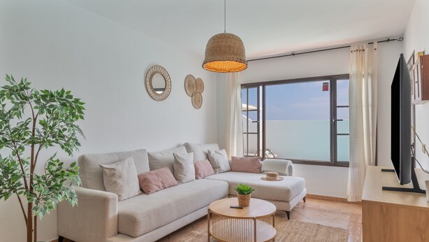 A modern living room with a sofa, a round coffee table, a potted plant, and a television. - Vacation Home 'Timanfaya' with Sea View, Private Pool and Wi-Fi (Tías)