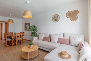 A living room with a sofa, dining table, chairs, and hanging lights.