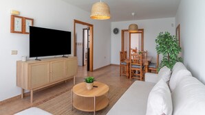 A modern living room with a TV, wooden furniture, a round coffee table, and a large plant. - Vacation Home 'Timanfaya' with Sea View, Private Pool and Wi-Fi (Tías)