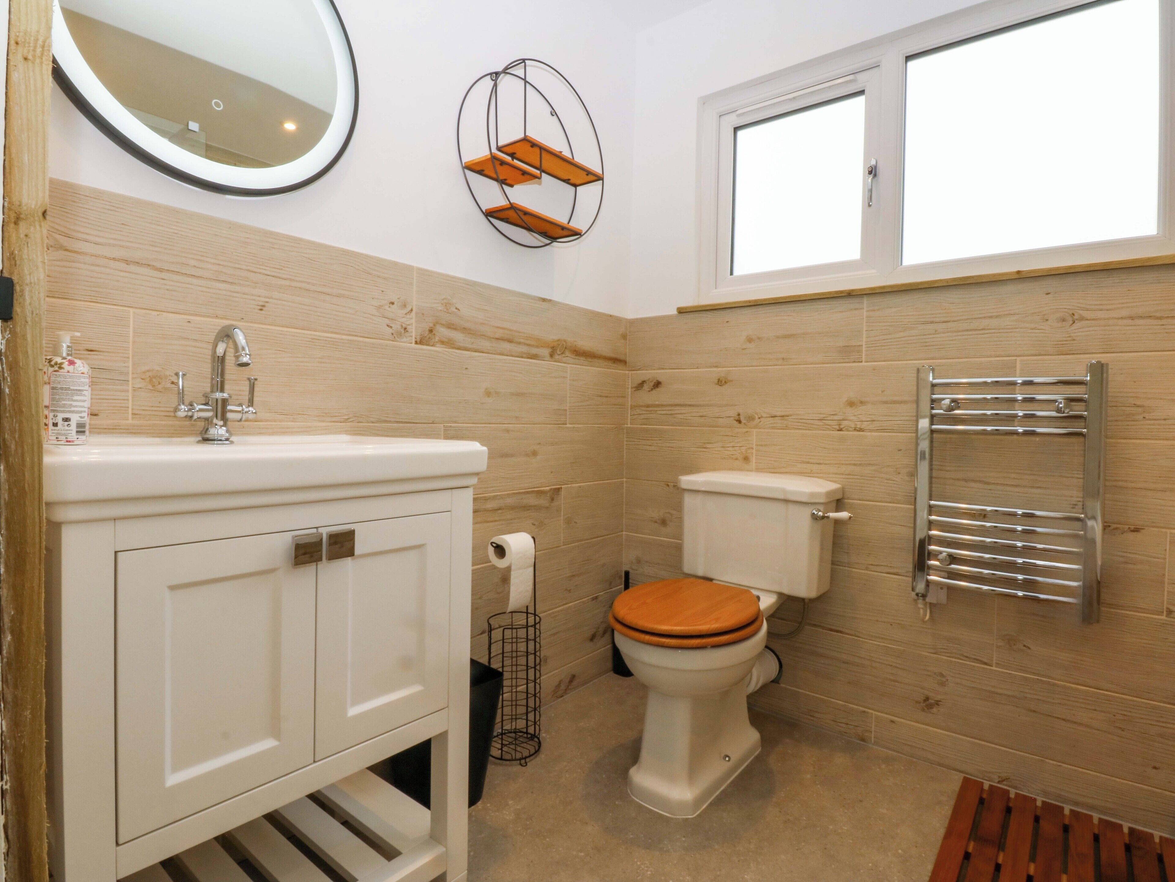 A bathroom with a white sink, wooden vanity, toilet, and a towel rack.