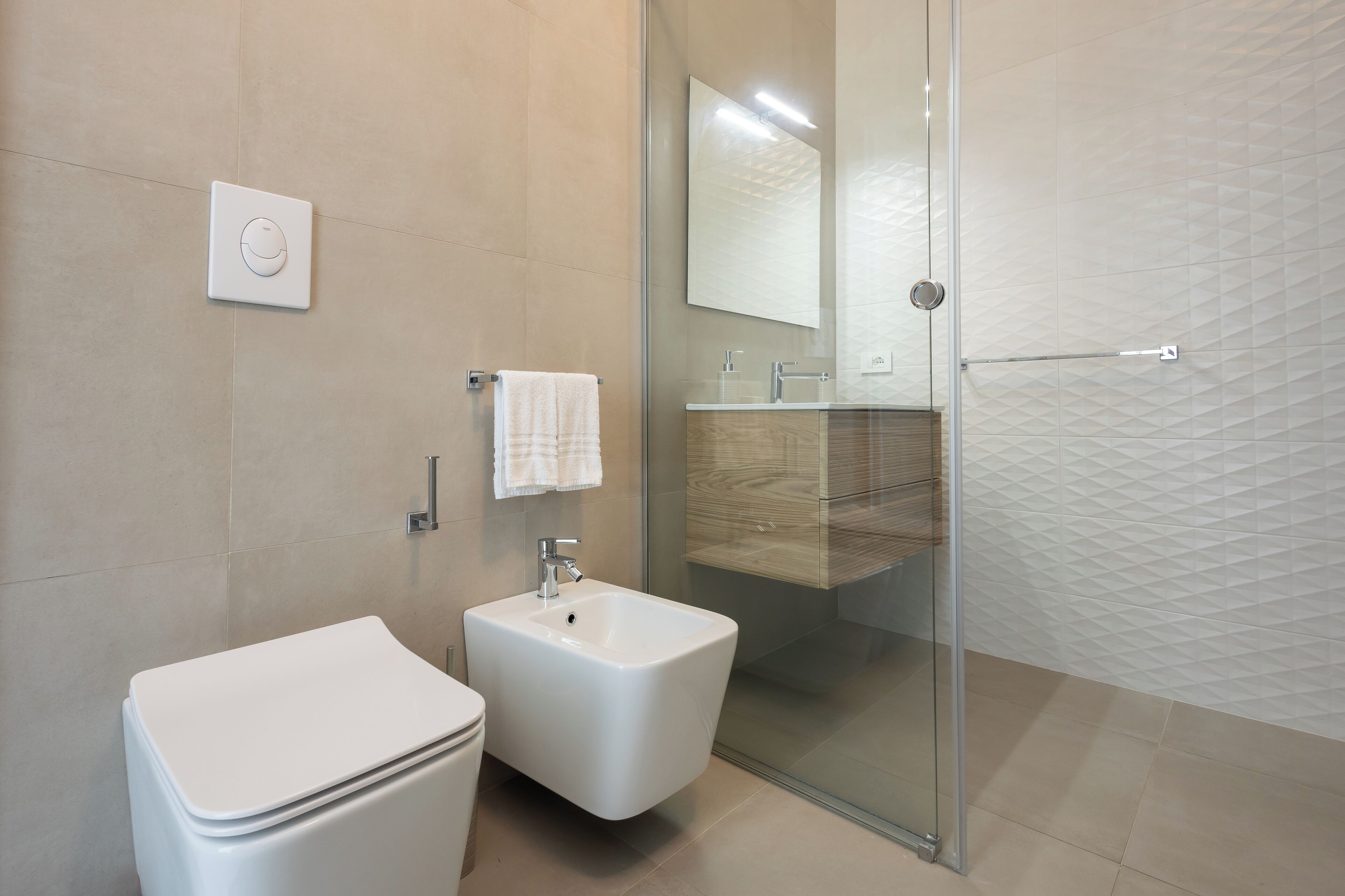 A modern bathroom with a toilet, bidet, and glass shower enclosure.