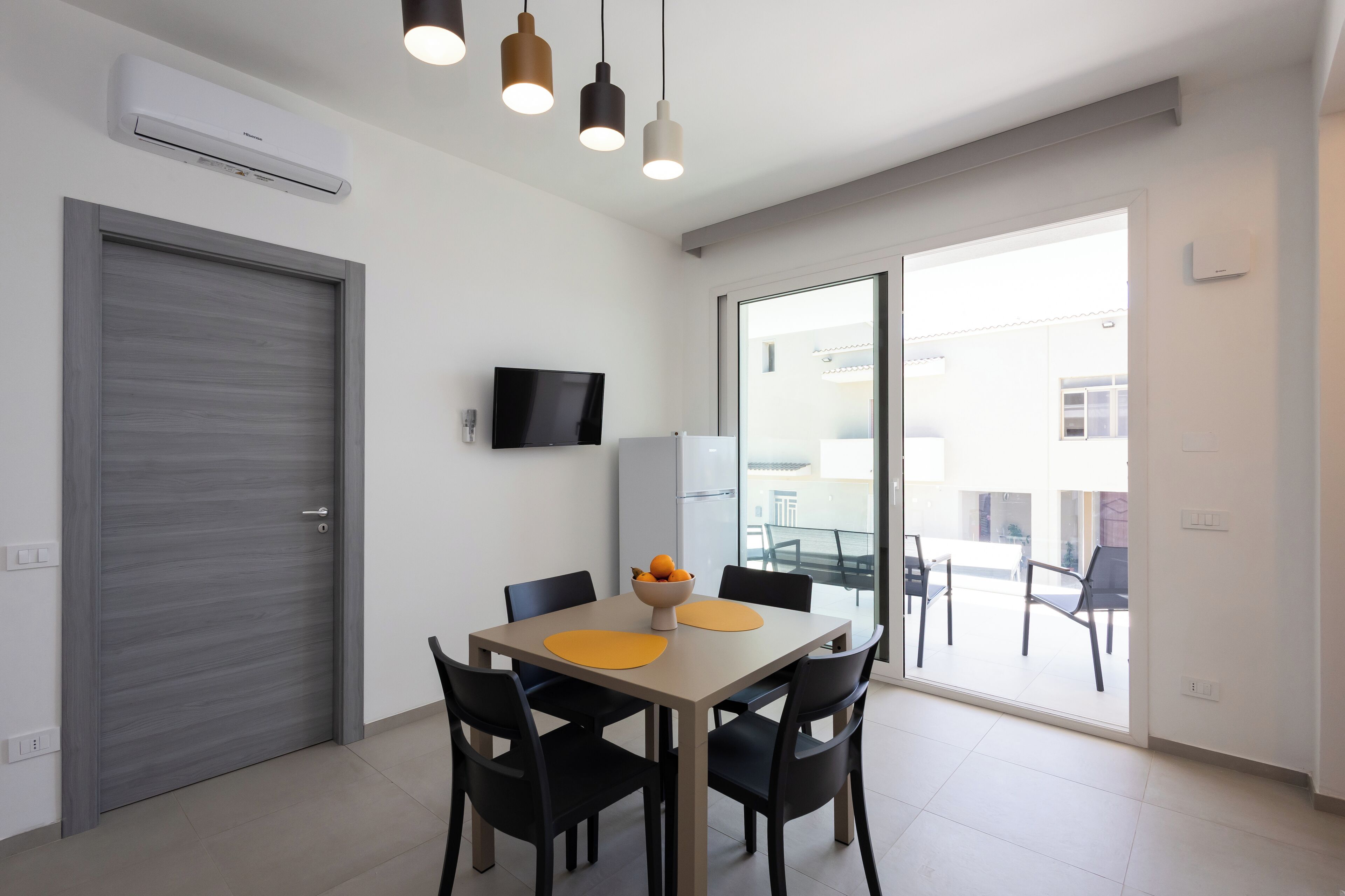 A modern dining area with a table, chairs, and a bowl of fruit.