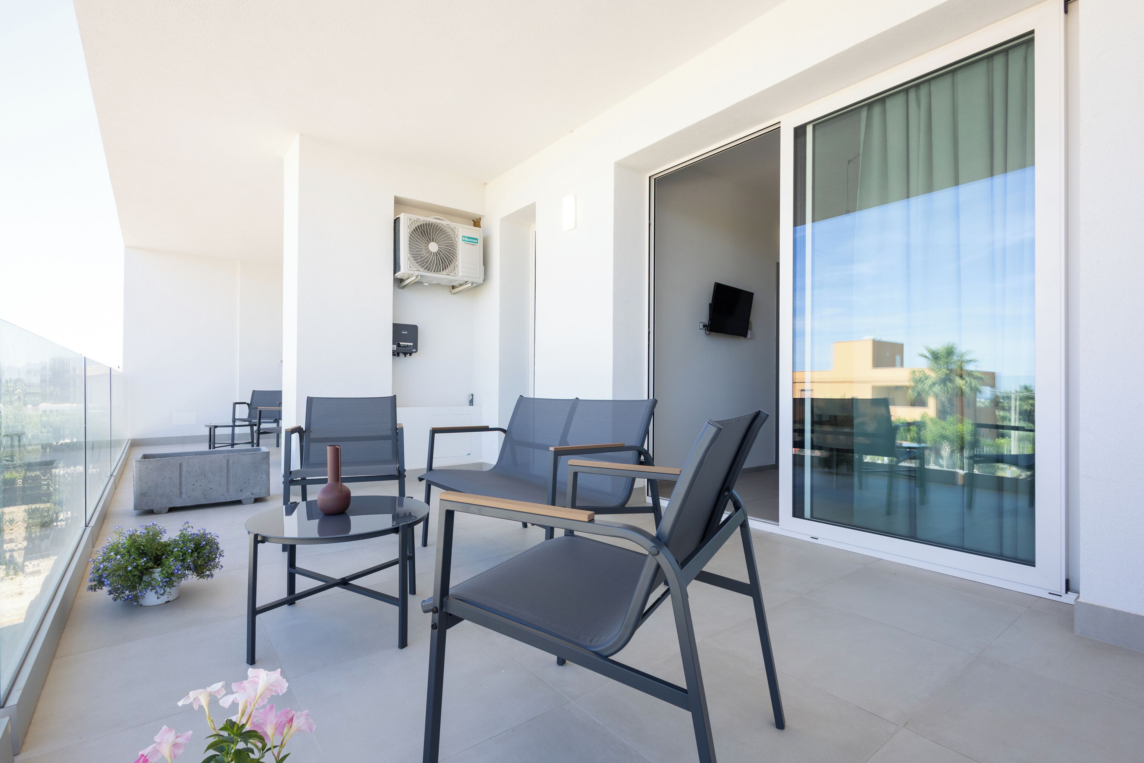 Un balcon avec deux chaises, une table et un pot de fleurs.