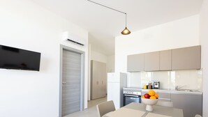 Una cocina moderna con horno empotrado, un comedor con mesa y sillas, y un televisor montado en la pared.