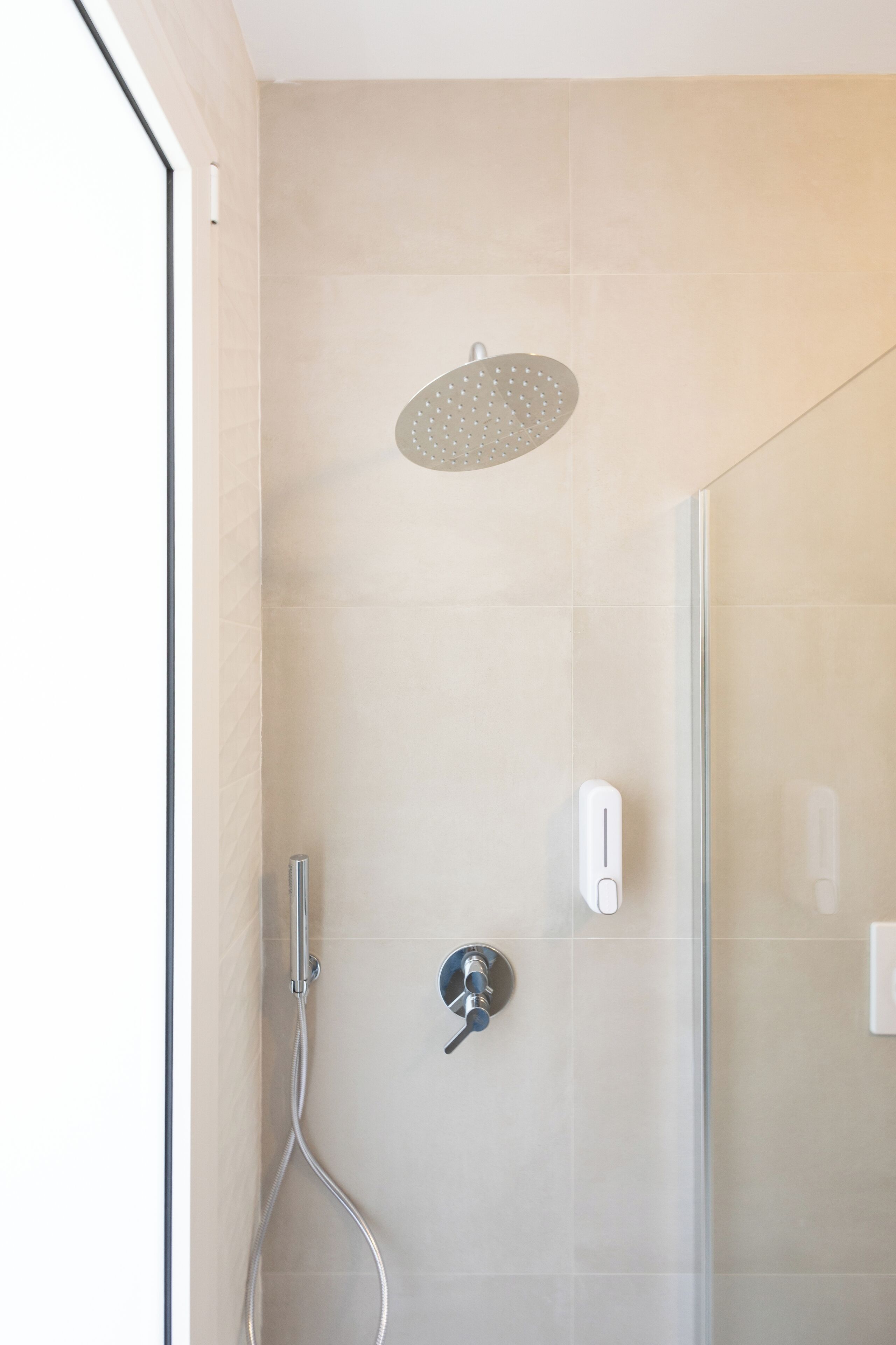 A modern shower with a handheld showerhead and a wall-mounted control panel.