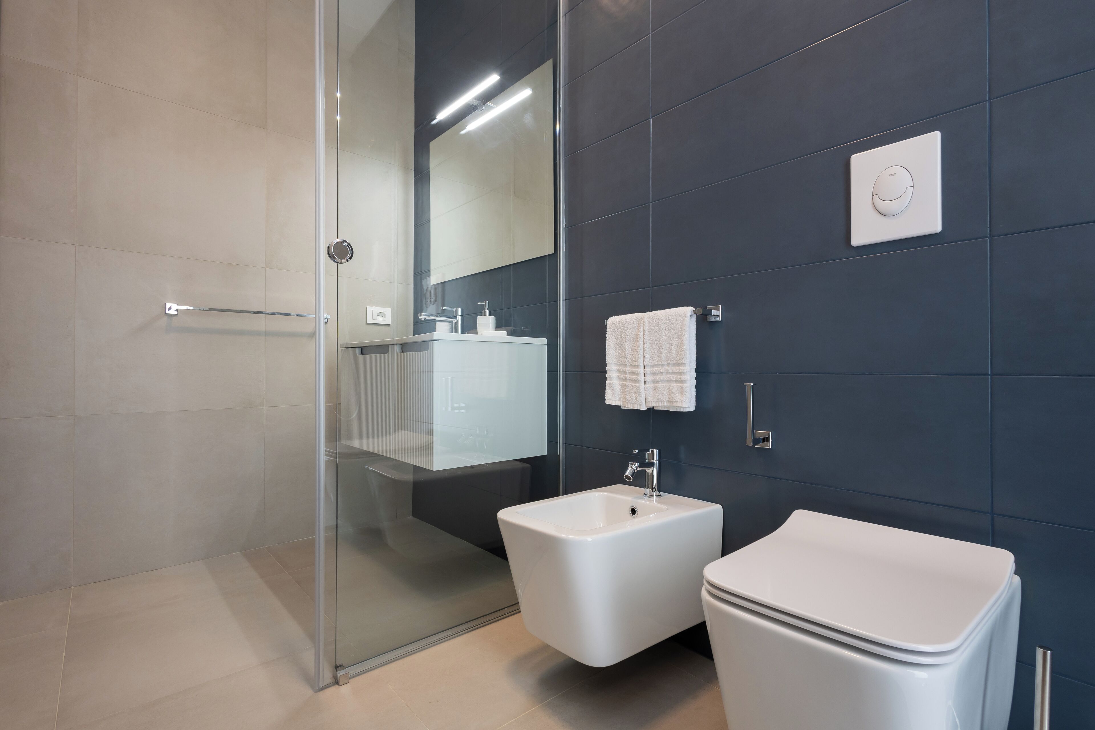 Un baño moderno con cabina de ducha de vidrio, un bidé, un lavamanos y un inodoro.
