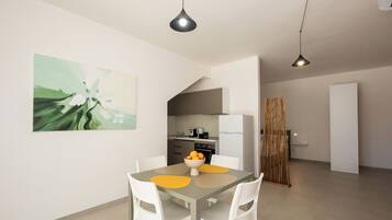 A modern kitchen with white cabinets, a dining area with a table and chairs, and a large abstract painting on the wall.