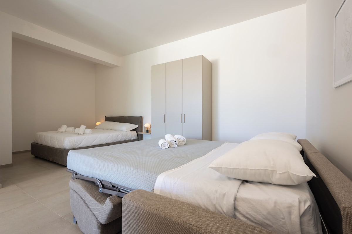 Ein modernes Hotelzimmer mit zwei Betten, einem Kleiderschrank und einer Sitzecke.