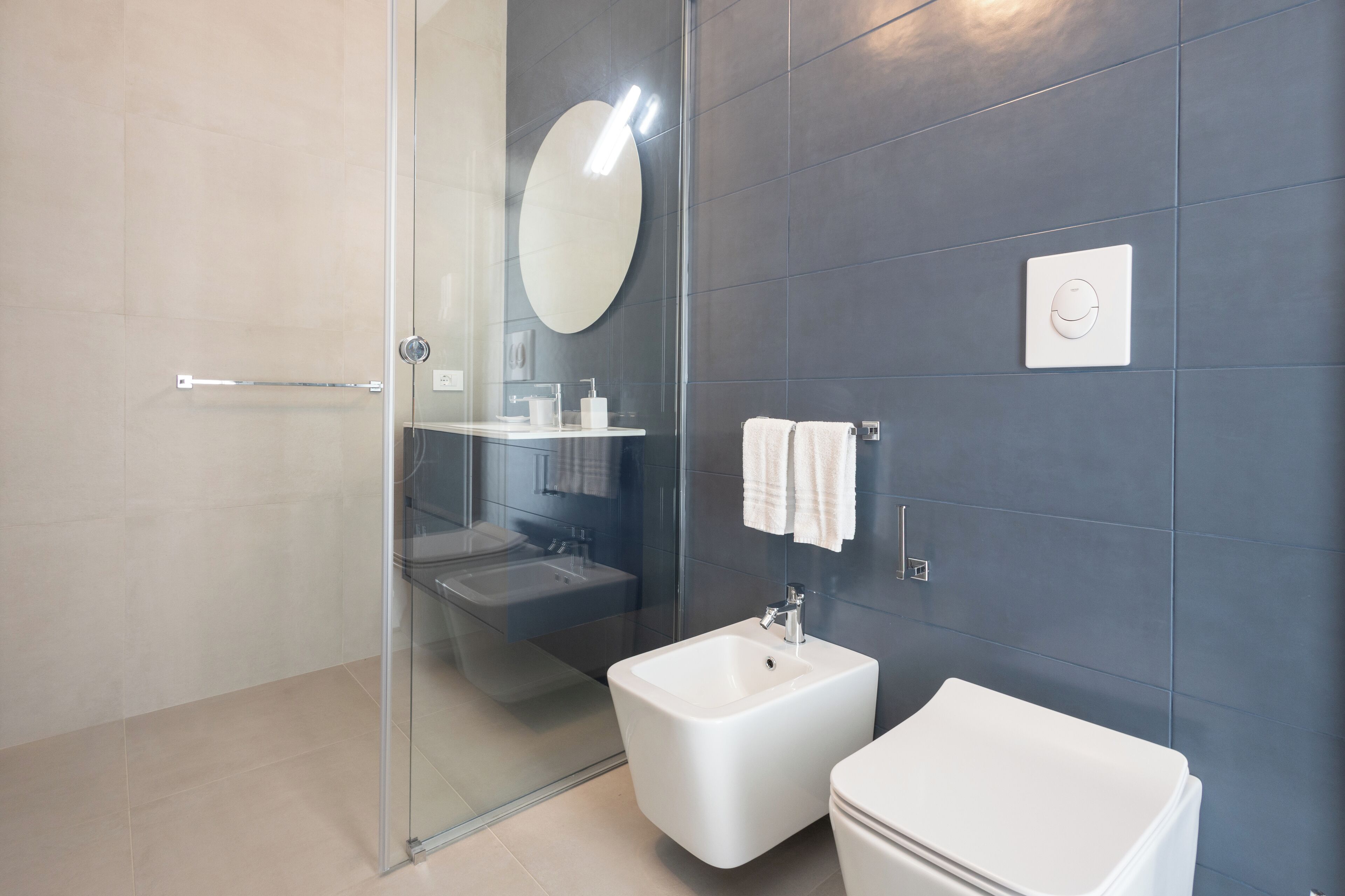 Une salle de bain moderne avec une douche à parois de verre, un lavabo blanc et des toilettes.