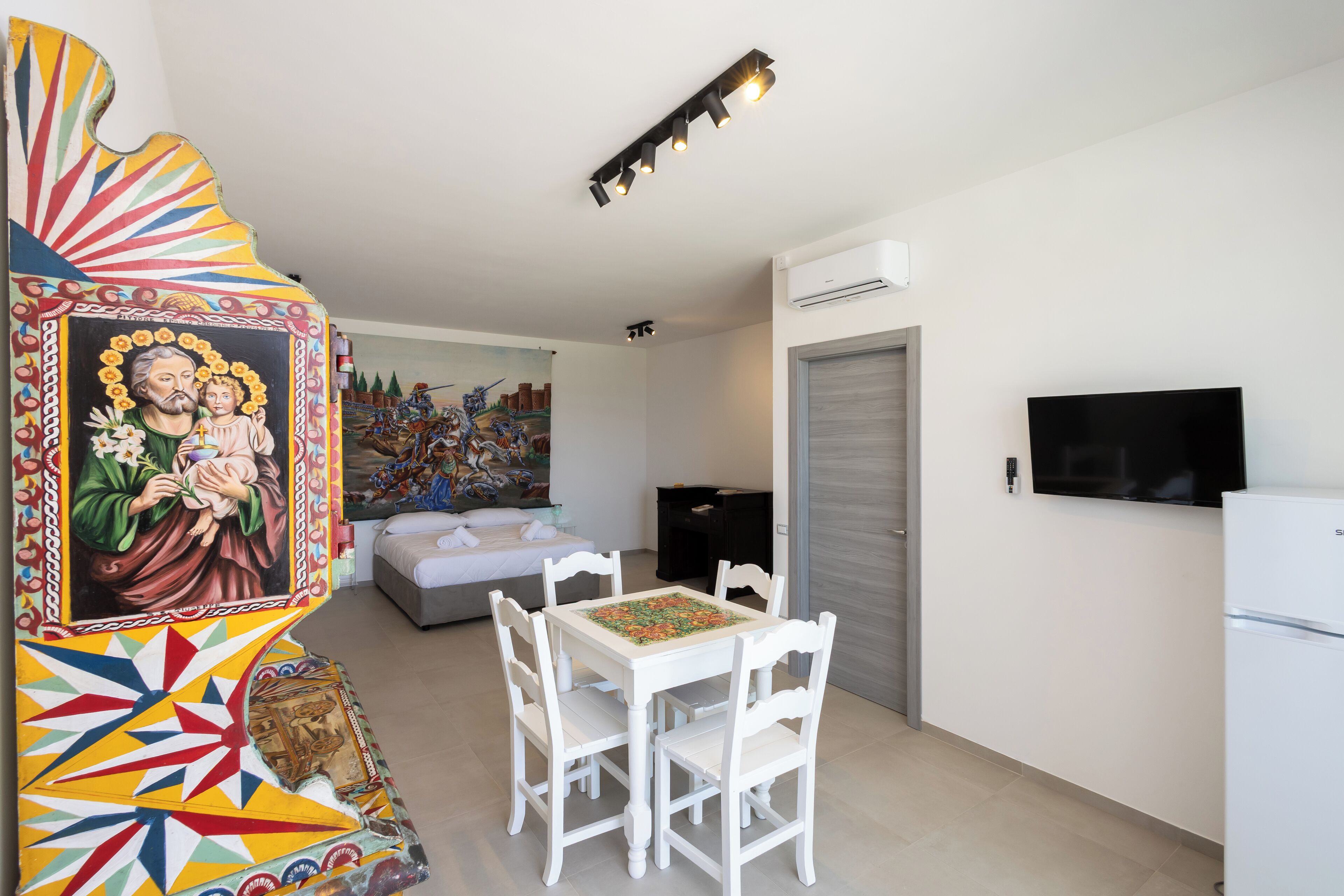Una habitación con una mesa de comedor, sillas, un televisor y un cuadro en la pared.