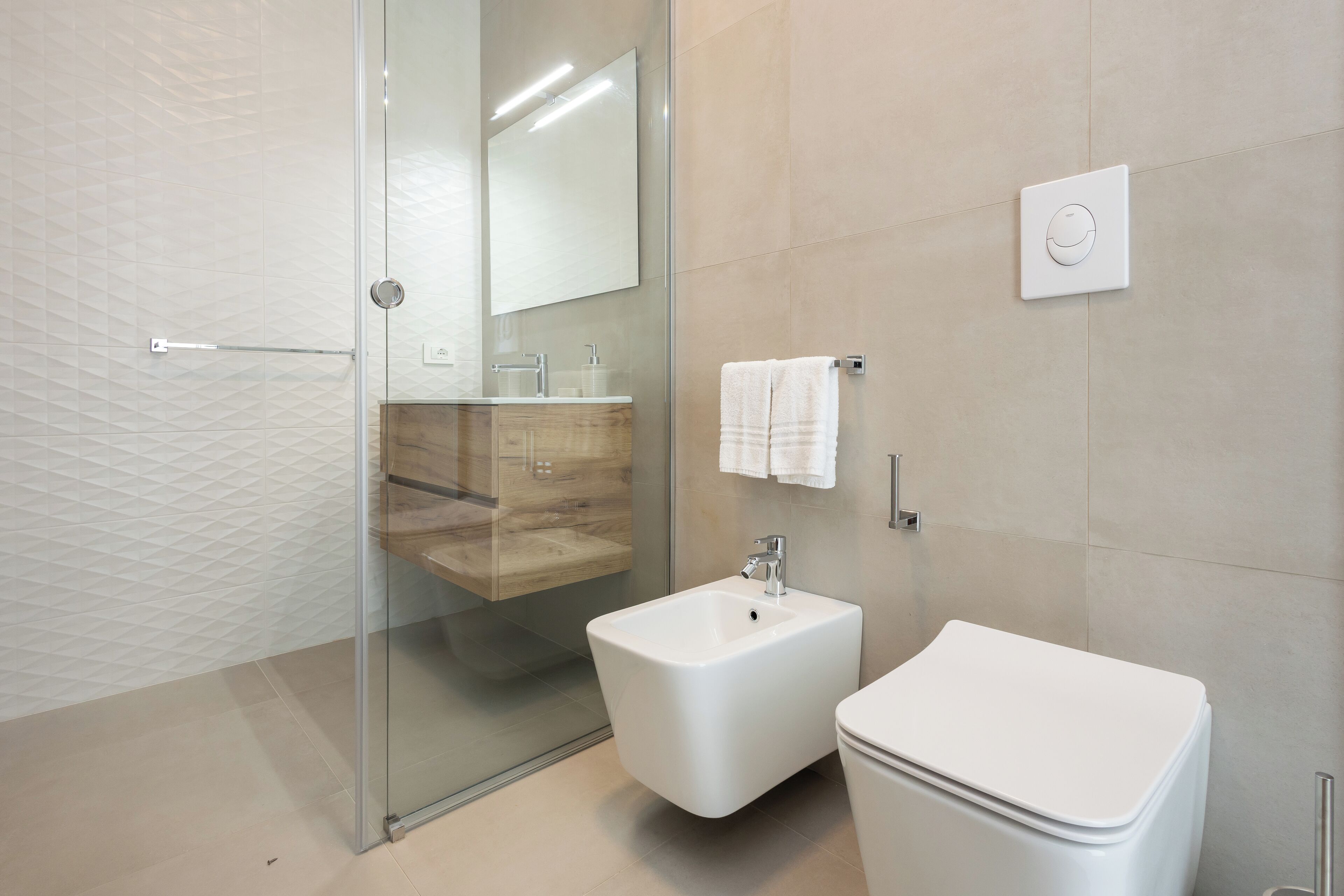 A modern bathroom with a glass shower enclosure, a white sink, and a toilet.