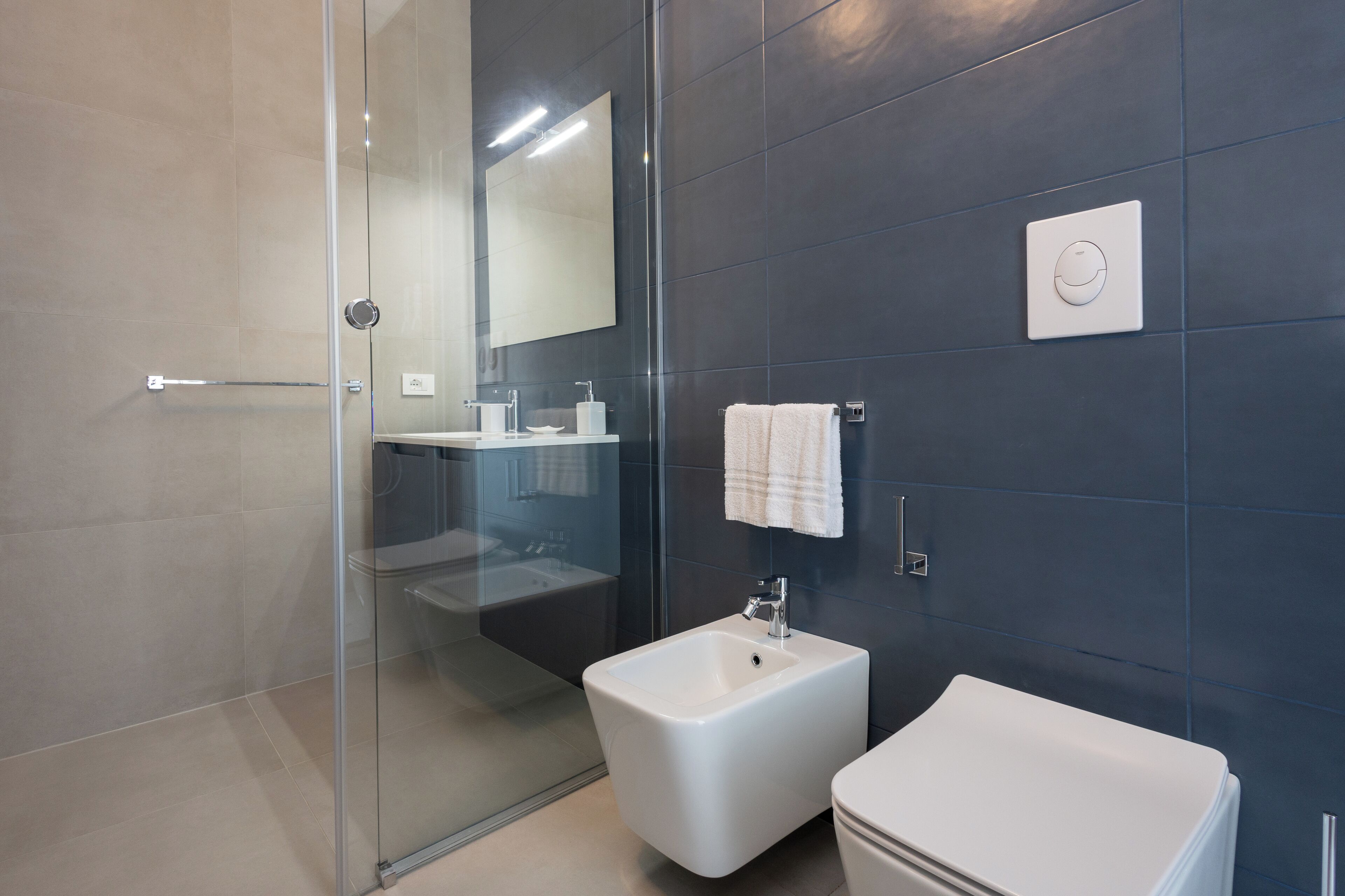 A modern bathroom with a glass shower enclosure, a bidet, and a toilet.