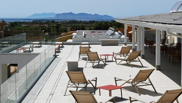 Terraza en la azotea con mobiliario exterior y vistas a montañas lejanas.