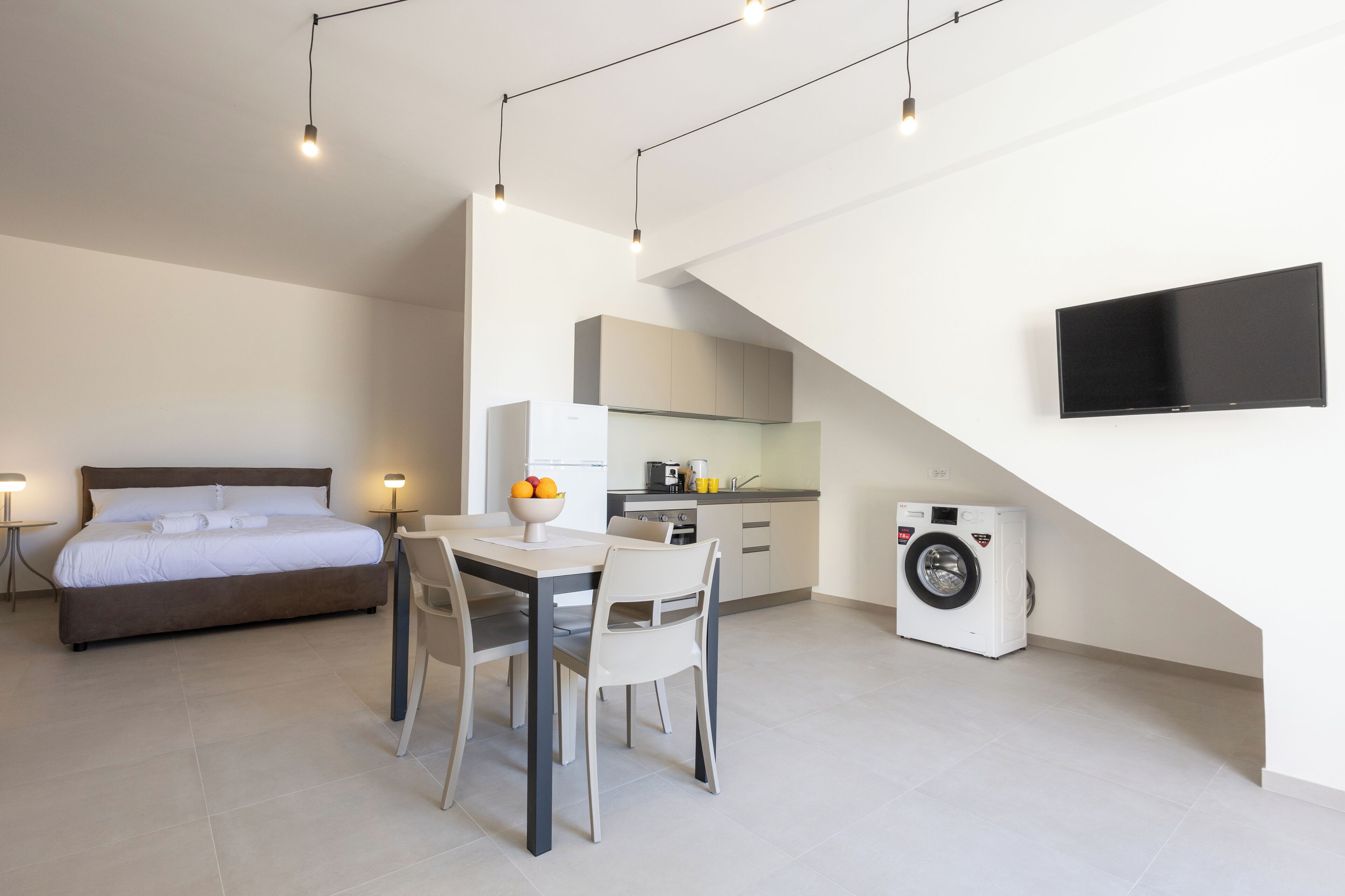 A modern bedroom with a bed, bedside tables, and a dining area with chairs and a table.