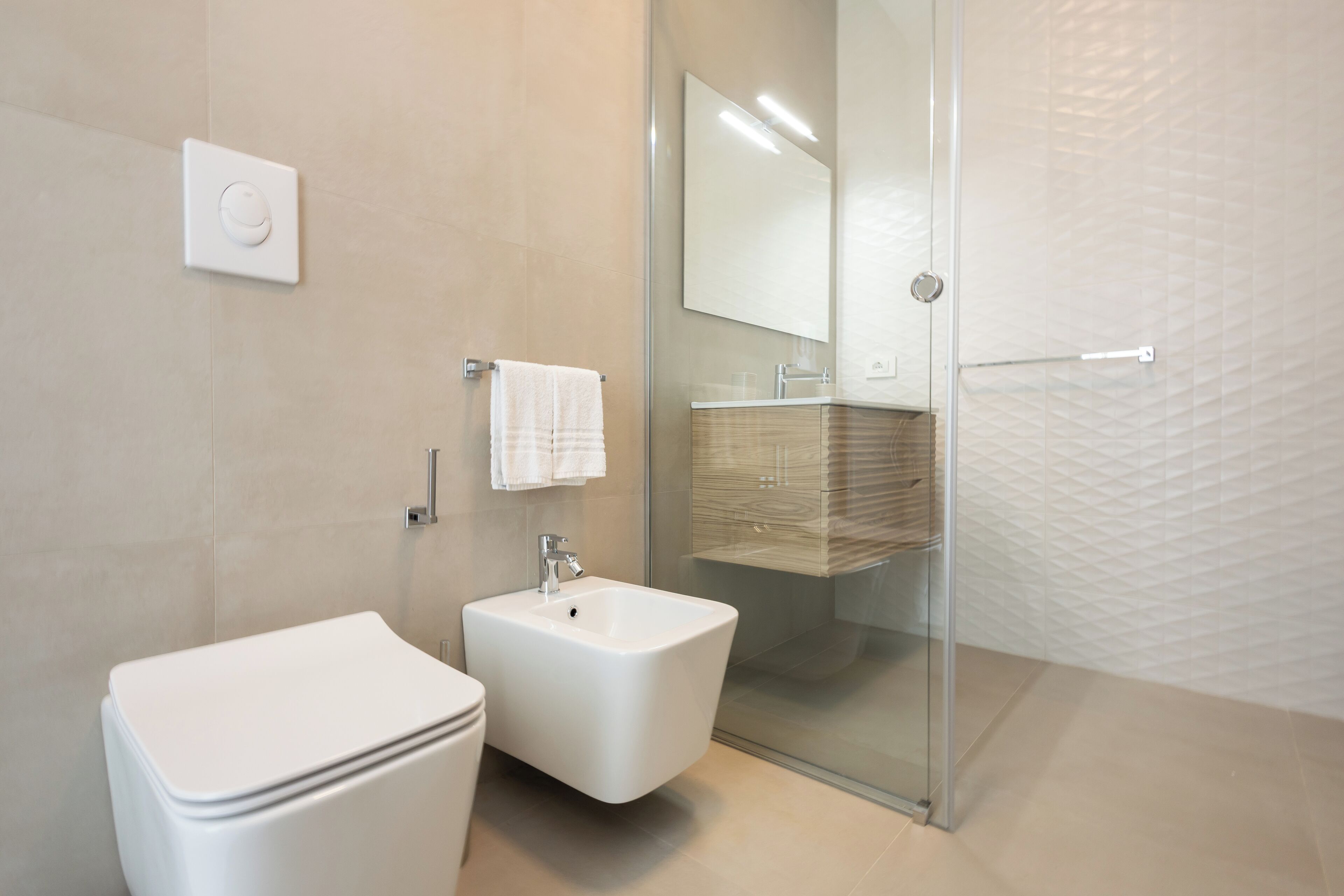 A modern bathroom with a toilet, bidet, and glass-enclosed shower.