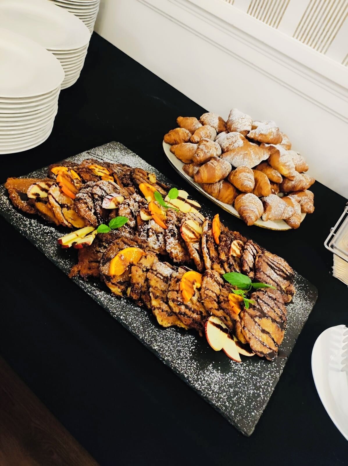 A buffet table with a variety of dishes, including sliced meats and pastries.