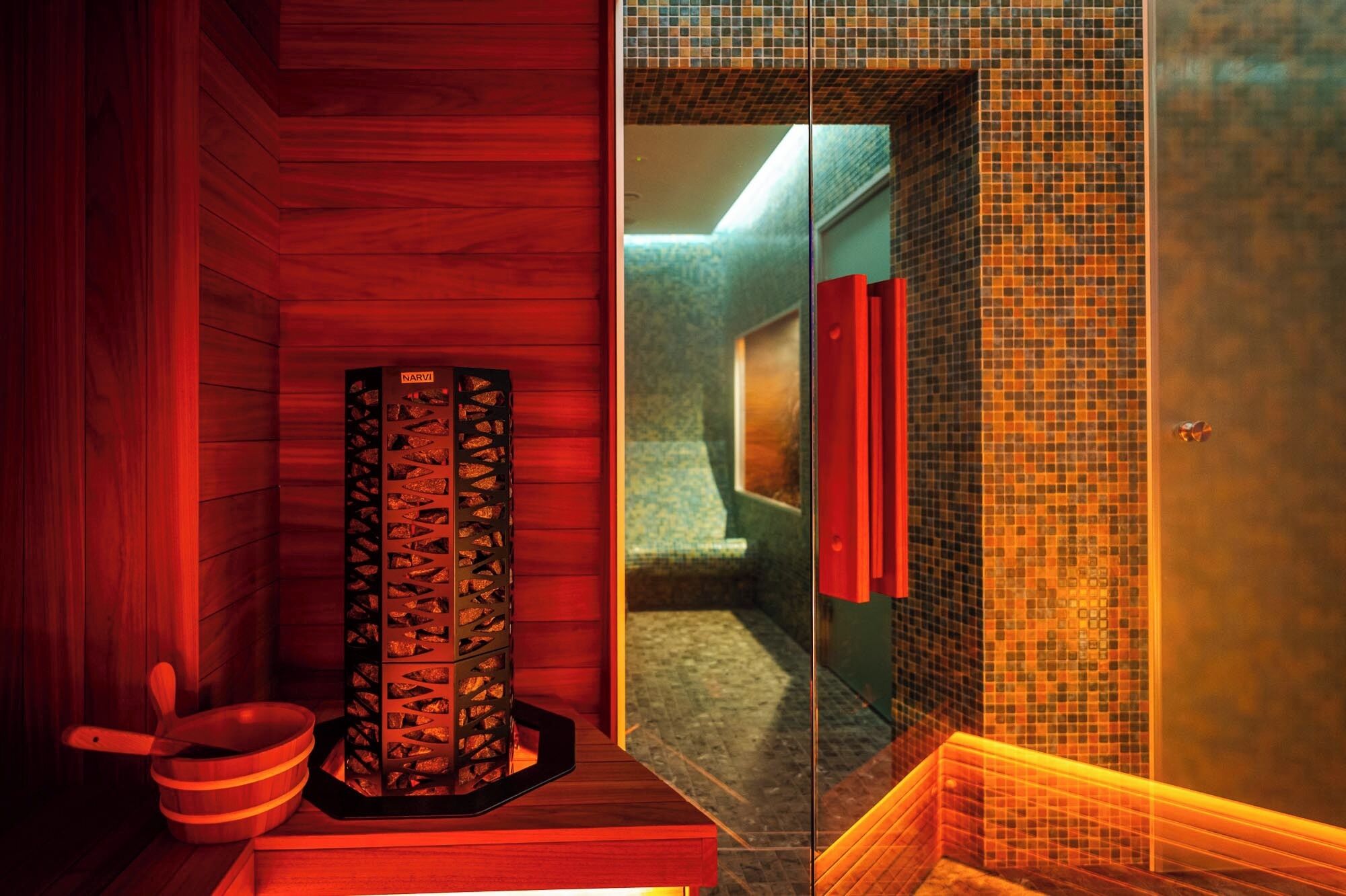 Een sauna met houten wanden, een houten bank en een betegelde doucheruimte.