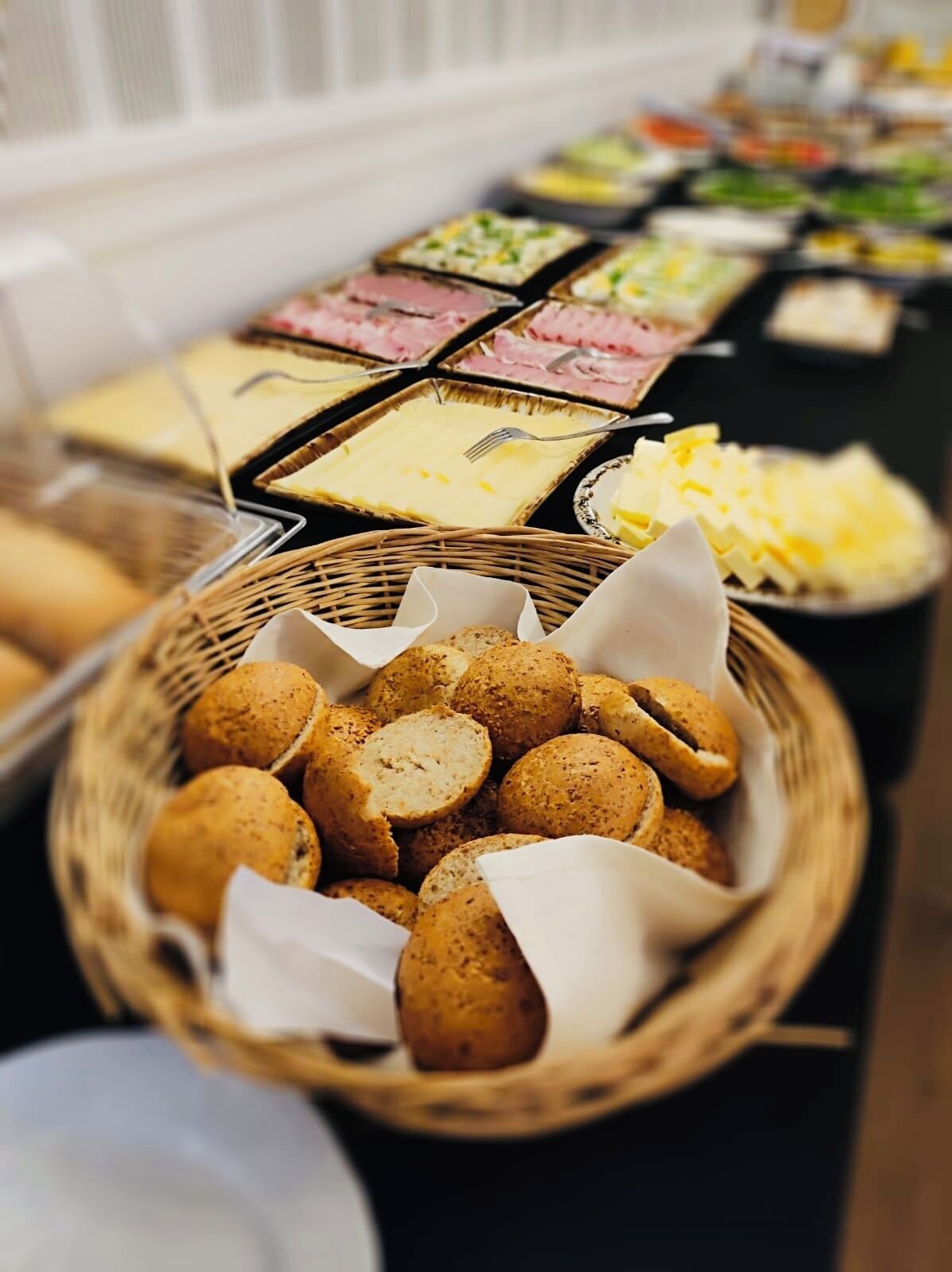 A buffet table with various food items, including a basket of cookies and several trays of different dishes.