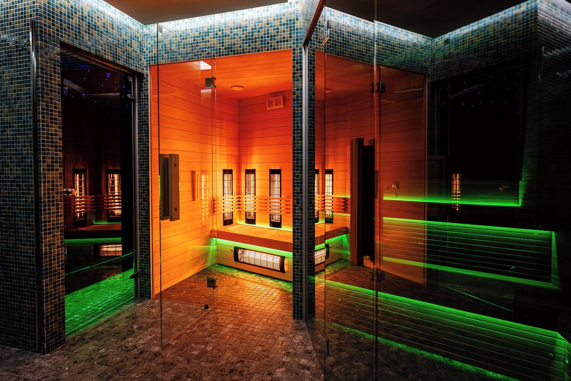 Una habitación moderna con paredes de vidrio, interior de madera e iluminación con detalles verdes.