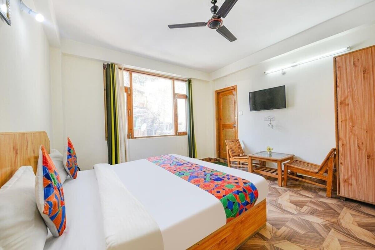 A hotel room with a bed, a desk, a chair, a TV, and a wardrobe.
