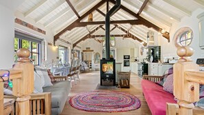 A spacious living area with a high ceiling, a fireplace, and a dining area with natural light. - The Zion Chapel, Cinderford - sleeps 4 guests  in 1 bedroom (Soudley, Forest of Dean)