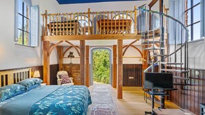 A bedroom with a bed, a chair, a desk, a TV, and a staircase leading to a loft. - The Zion Chapel, Cinderford - sleeps 4 guests  in 1 bedroom (Soudley, Forest of Dean)