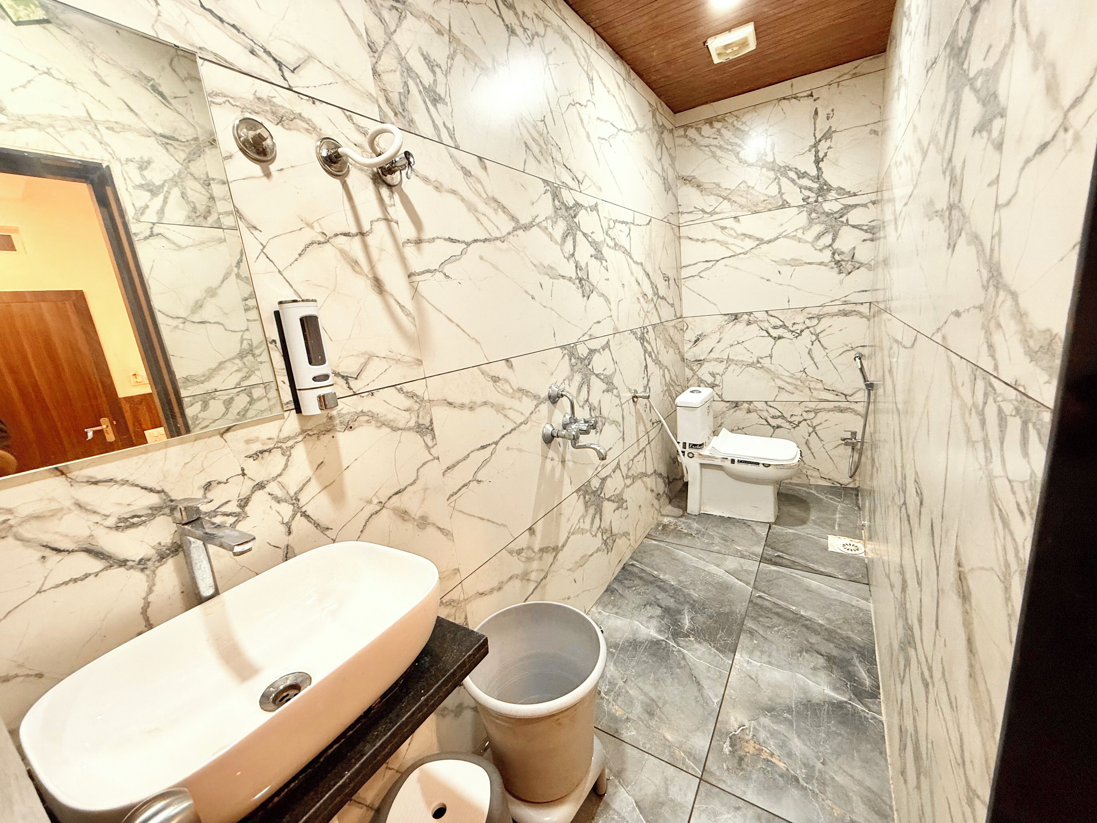 Een badkamer met een marmeren wastafel, toilet en een douchetoilet.
