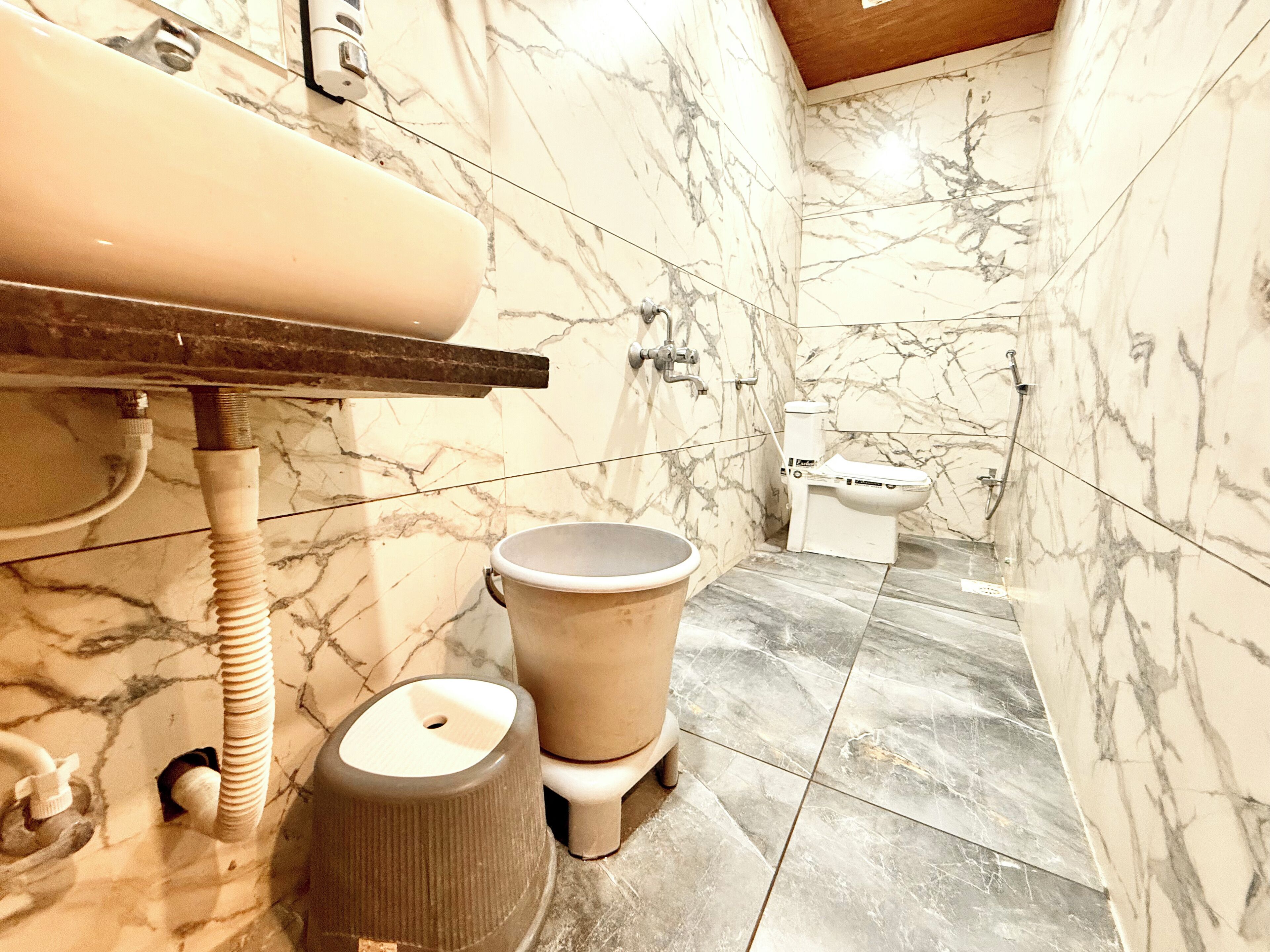 Un baño con paredes de mármol, un inodoro, un bidé y un lavabo con grifo.