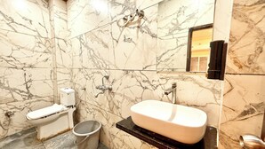Une salle de bain avec un mur en marbre, des toilettes, un lavabo et un seau.