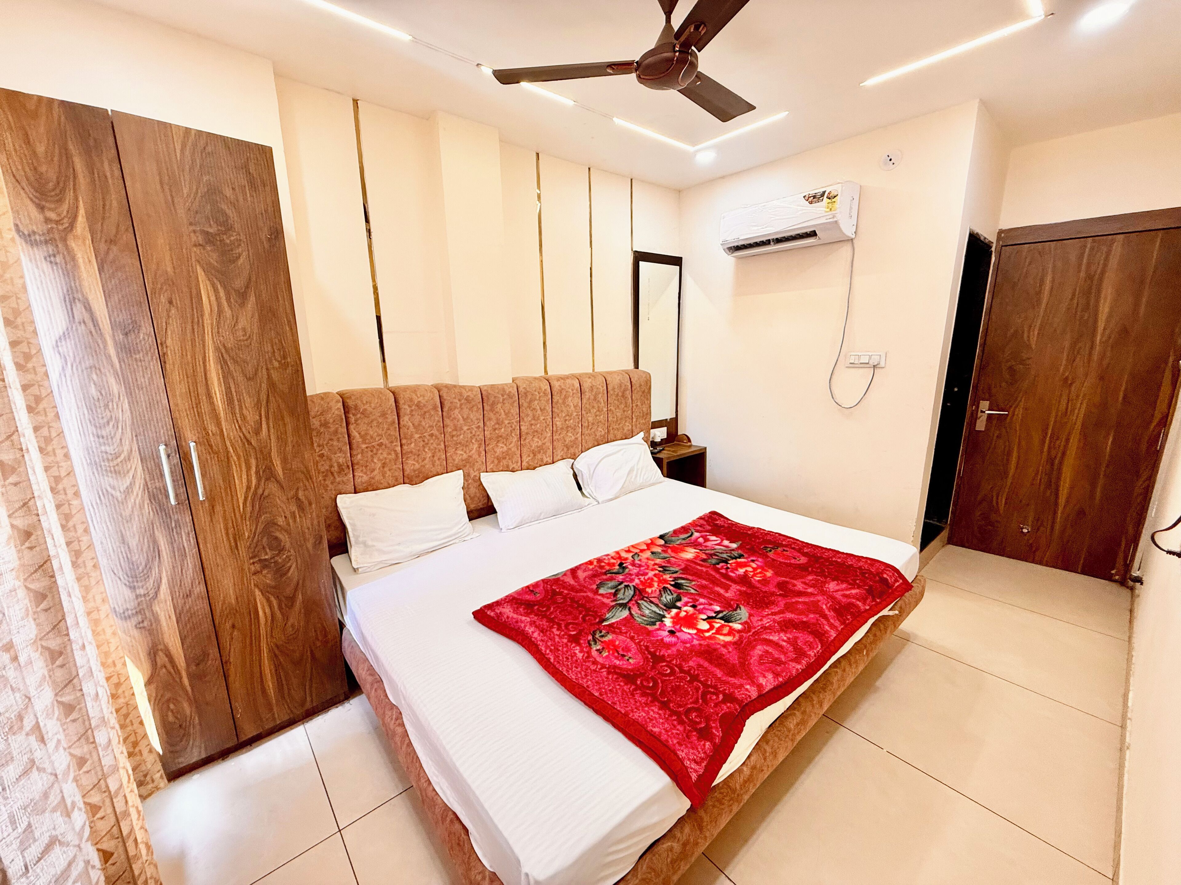 Ein Schlafzimmer mit Bett, Deckenventilator, Klimaanlage, Kleiderschrank und einer Tür.