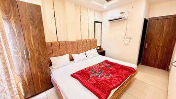 Un dormitorio con cama, ventilador de techo, aire acondicionado, armario y una puerta.