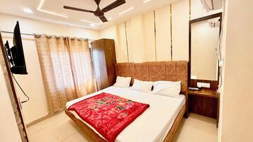 A modern hotel room with a large bed, a ceiling fan, a TV mounted on the wall, and a mirror.