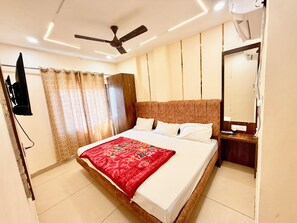 Habitación de hotel moderna con una cama grande, ventilador de techo, televisión montada en la pared y un espejo.